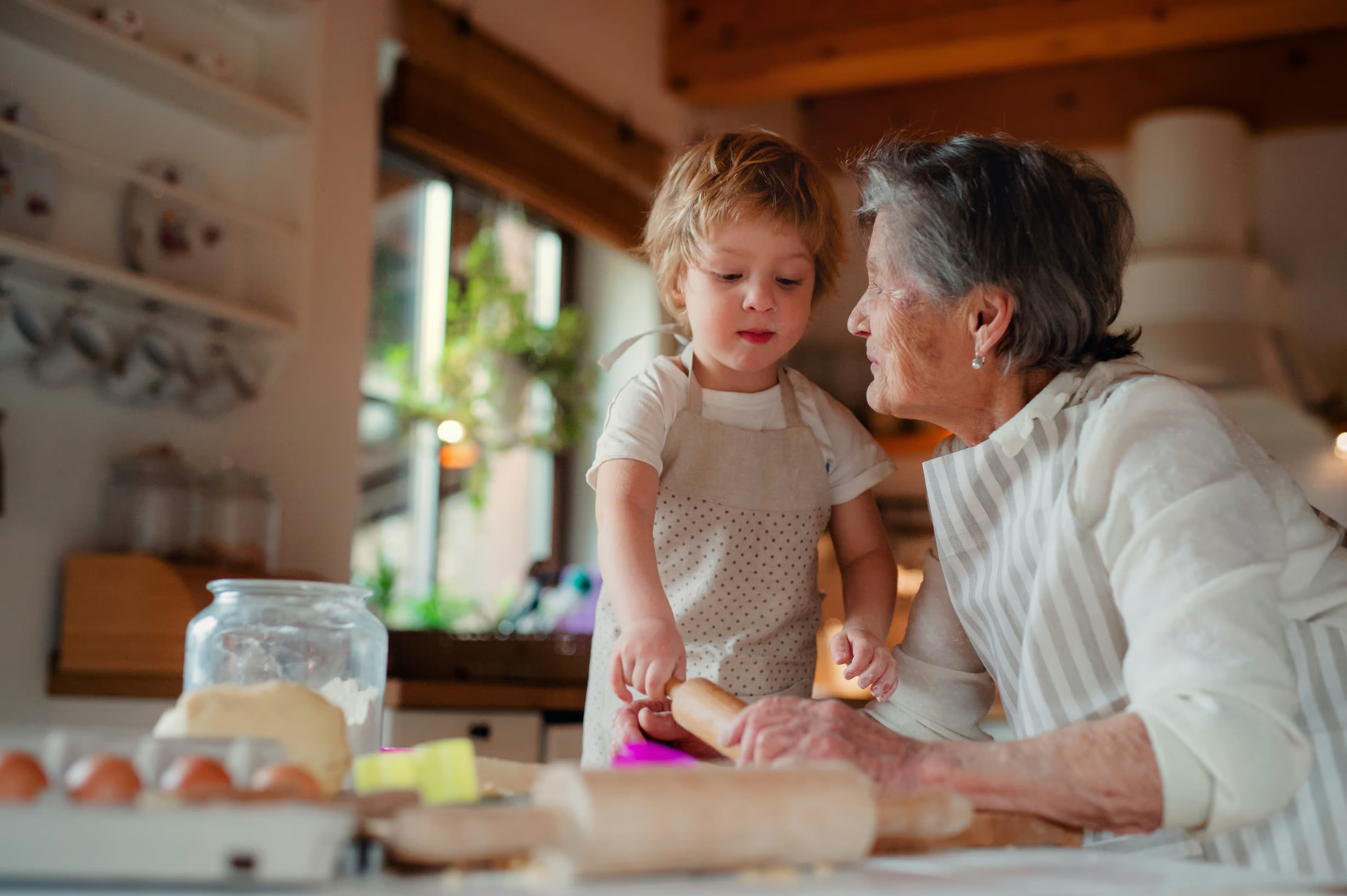 A grandmother and her grandchild baking together in a sunlit kitchen
