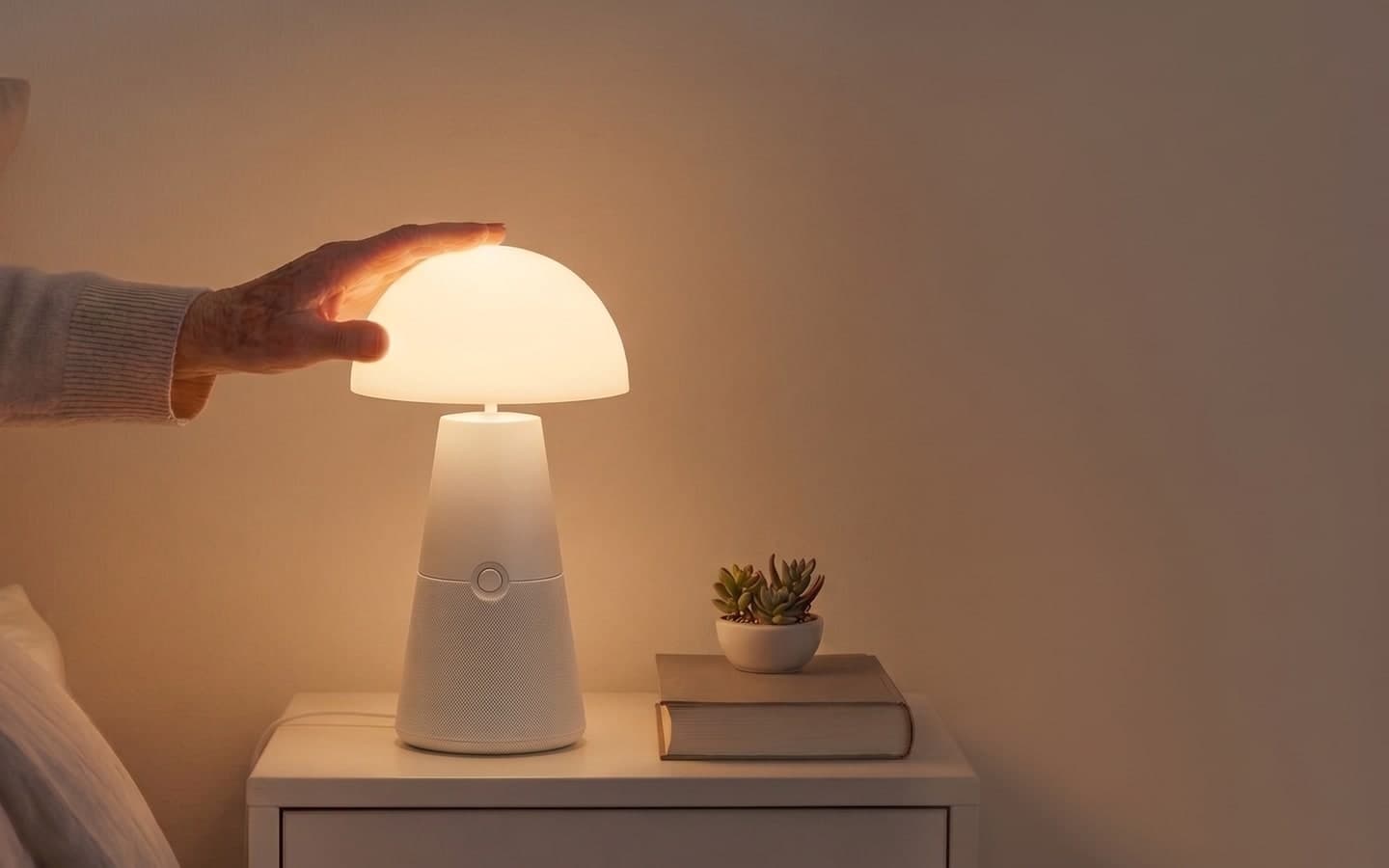 A hand reaching to dim a softly-lit Lutso lamp on a warm bedside table