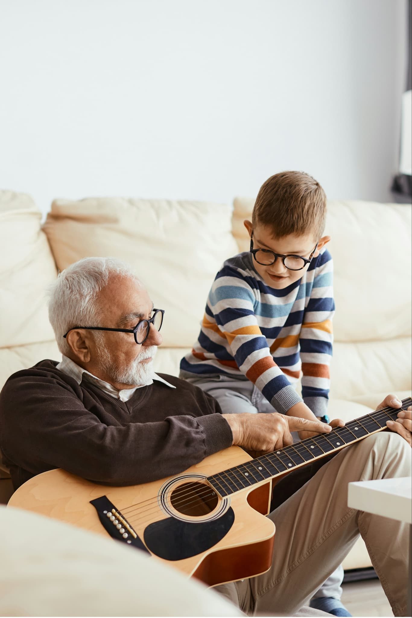 Grandfather teaching his grandson guitar at home